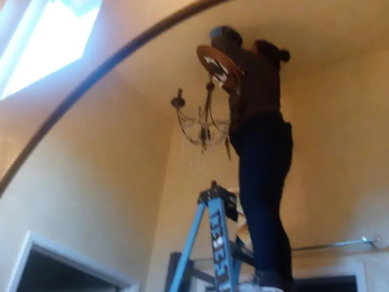 Electrician installing a chandelier in a Daly City residence